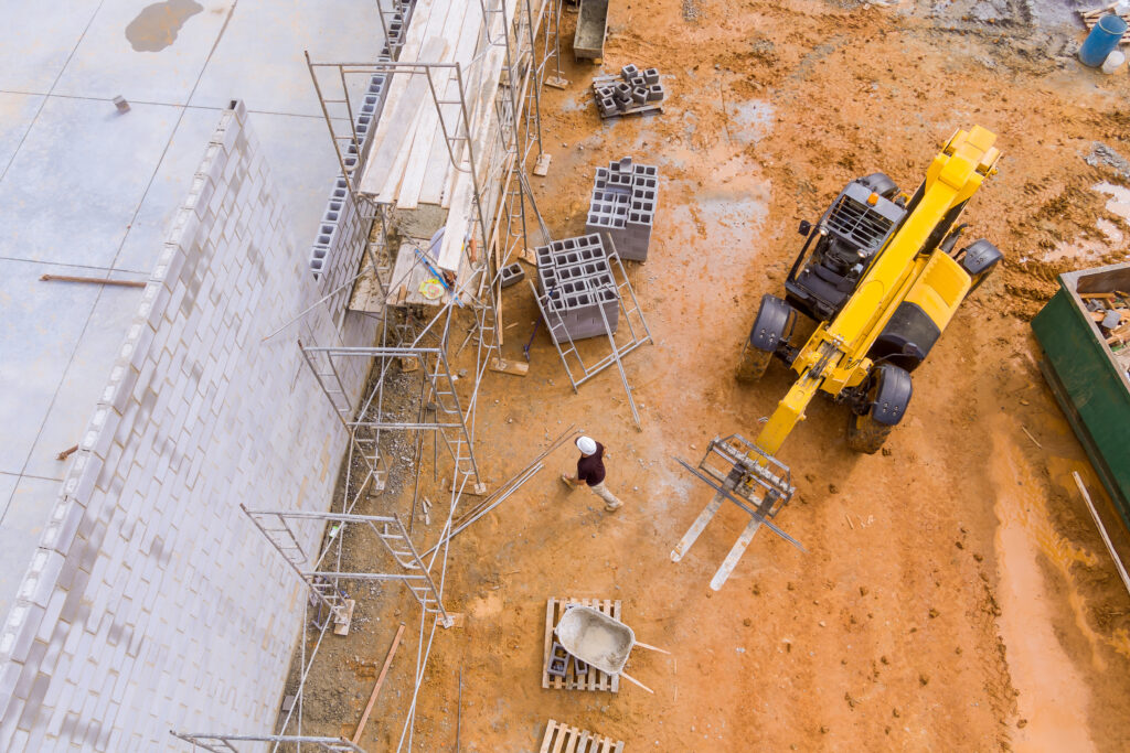 Bricklayer builder make working concrete wall from concrete blocks standing on scaffolds