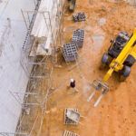 Bricklayer builder make working concrete wall from concrete blocks standing on scaffolds