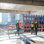 A group of engineers standing on construction site, talking.