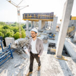 Man supervising the process of house construction walking with drawings on the structure outdoors